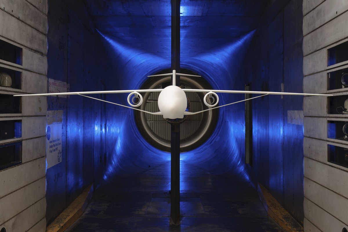 Aircraft model with long thin wings mounted in a blue-lit wind tunnel test section