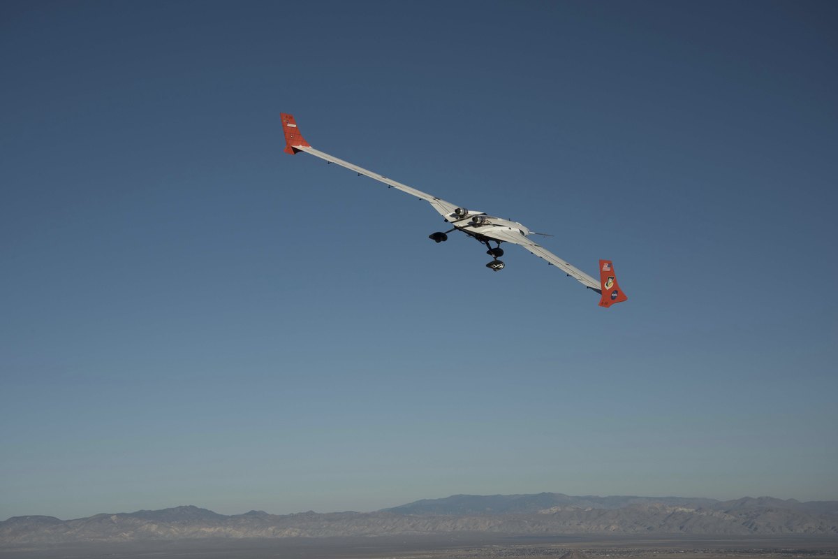 X-56A flexible-wing research aircraft banking against a deep blue dusk sky above desert mountains